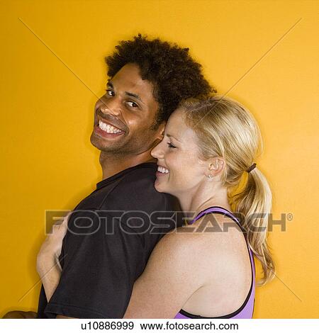 Stock Photo - Caucasian woman hugging African-American man.. Fotosearch