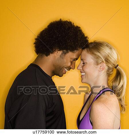 Stock Image - Caucasian woman with head against African-American male's head.. Fotosearch