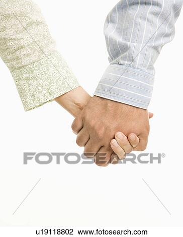 Stock Image - Close up of woman and man holding hands.. Fotosearch
