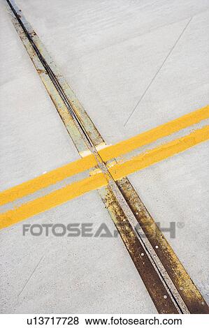 Stock Photo - Detail of solid double yellow line in road crossing metal strips in cement.. Fotosearch