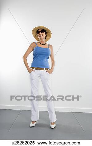 Stock Photography - Full length portrait of Caucasian woman wearing sunglasses and straw hat.. Fotosearch