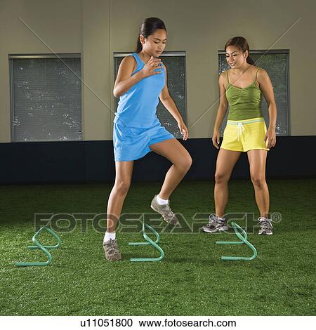 Girl jumping step hurdles in indoor gym while woman coach watches. View Large Photo Image Stock Image - Girl jumping step hurdles in indoor gym while woman coach watches.. Fotosearch