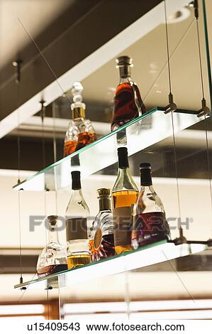 Stock Image - Glass shelves with liquor bottles.. Fotosearch