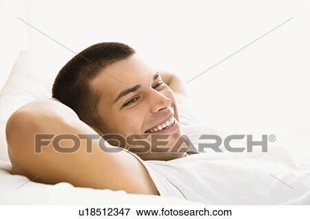 Stock Photo - Handsome Caucasian mid adult man lying with hands behind head and smiling.. Fotosearch