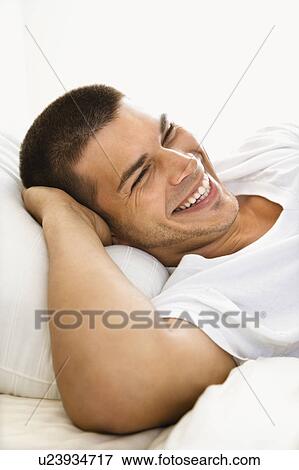 Stock Photo - Handsome Caucasian mid adult man lying with hands behind head smiling.. Fotosearch