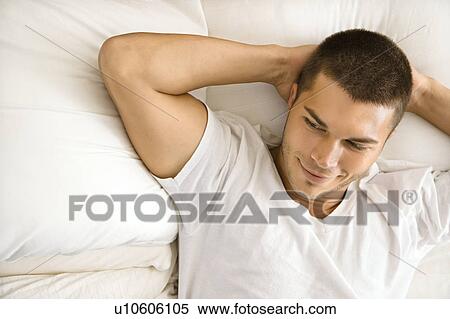 Stock Photography - Handsome Caucasian mid adult man lying with hands behind head smiling.. Fotosearch
