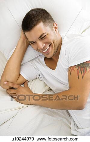 High angle view of handsome Caucasian mid adult man lying in bed smiling. View Large Photo Image Stock Photo - High angle view of handsome Caucasian mid adult man lying in bed smiling.. Fotosearch