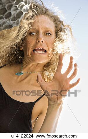 Picture - Low angle view of Caucasian mid-adult woman making facial expression and gesturing to viewer.. Fotosearch