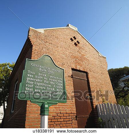 Stock Image - Low angle view of generator house for Cape Fear lighthouse at Bald Head Island, North Carolina.. Fotosearch