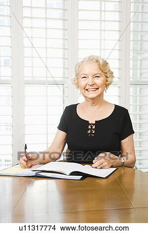 Mature Caucasian woman writing in calendar. View Large Photo Image Picture - Mature Caucasian woman writing in calendar.. Fotosearch