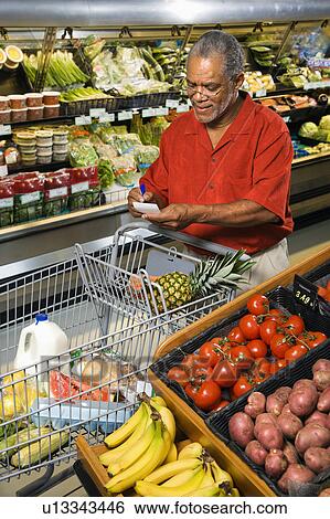 Middle aged African American man in grocery store writing on shopping list. View Large Photo Image Stock Photograph - Middle aged African American man in grocery store writing on shopping list.. Fotosearch