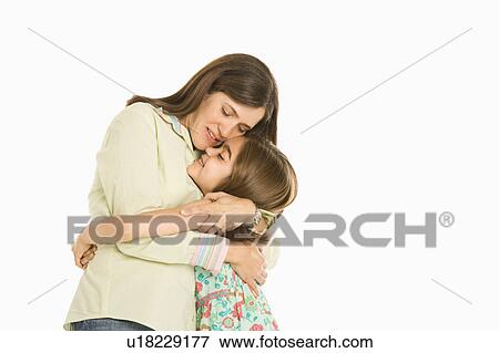 Stock Photo - Mother and daughter embracing standing against white background.. Fotosearch