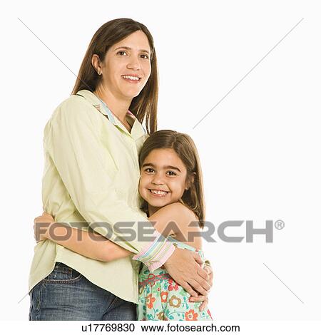 Stock Image - Mother and daughter standing holding eachother smiling.. Fotosearch
