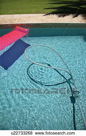 Stock Photo - Pink float and vacuum hose in swimming pool.. Fotosearch