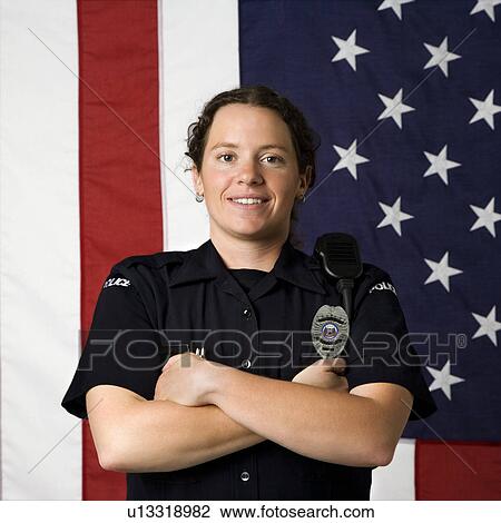 Portrait of mid adult Caucasian policewoman standing with arms crossed with American flag as backdrop smiling at viewer. View Large Photo Image Stock Image - Portrait of mid adult Caucasian policewoman standing with arms crossed with American flag as backdrop smiling at viewer.. Fotosearch