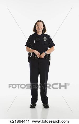 Stock Image - Portrait of mid adult Caucasian policewoman standing with hands on gun holster looking at viewer smiling.. Fotosearch