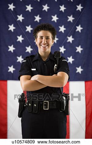 Portrait of mid adult Caucasian policewoman standing with arms crossed and American flag as backdrop smiling at viewer. View Large Photo Image Stock Photo - Portrait of mid adult Caucasian policewoman standing with arms crossed and American flag as backdrop smiling at viewer.. Fotosearch