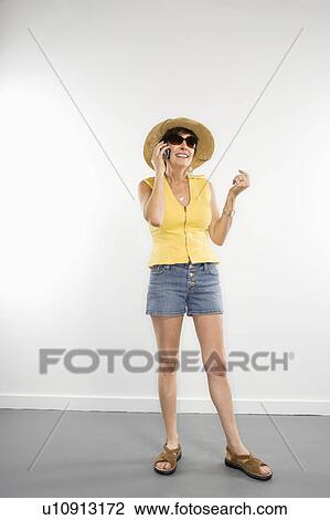 Stock Image - Portrait of pretty Caucasian woman in summer attire talking on cellphone.. Fotosearch