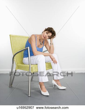 Stock Photo - Portrait of pretty Caucasian woman sitting in modern chair.. Fotosearch