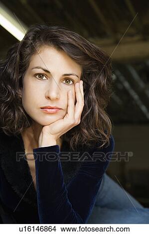 Picture - Portrait of pretty mid adult Caucasian woman with head on hand making eye contact.. Fotosearch