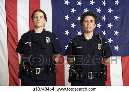 Portrait of two mid adult Caucasian policewomen standing with arms behind their backs and American flag as backdrop. View Large Photo Image Picture - Portrait of two mid adult Caucasian policewomen standing with arms behind their backs and American flag as backdrop.. Fotosearch