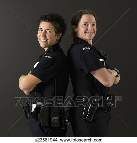 Portrait of two mid adult Caucasian policewomen standing back to back looking over their shoulders smiling at viewer. View Large Photo Image Picture - Portrait of two mid adult Caucasian policewomen standing back to back looking over their shoulders smiling at viewer.. Fotosearch
