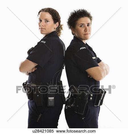 Stock Photography - Portrait of two mid adult Caucasian policewomen standing back to back looking over their shoulders smiling at viewer.. Fotosearch