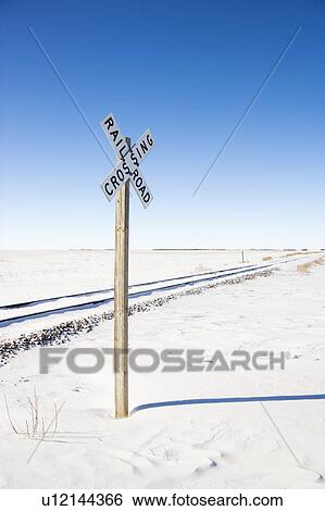 Stock Photograph - Railroad crossing sign by tracks in rural desolate snowy landscape.. Fotosearch