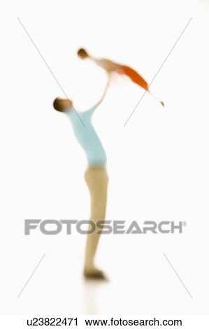 Stock Image - Soft focus father holding up boy overhead.. Fotosearch