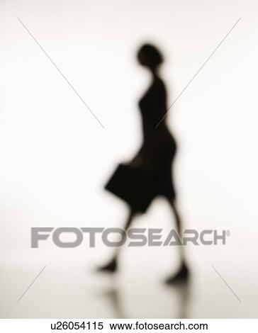 Stock Photography - Soft focus silhouette of walking businesswoman holding briefcase.. Fotosearch