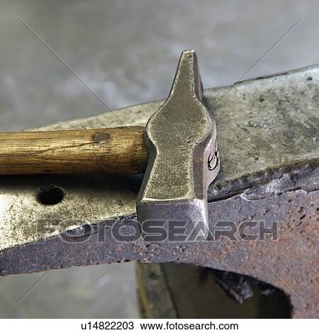 Stock Image - Still life shot of hammer laying on anvil.. Fotosearch