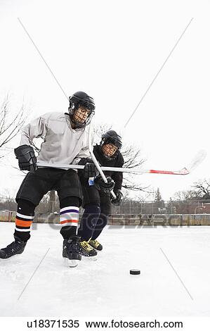 Two boys in ice hockey uniforms playing hockey on ice rink. View Large Photo Image Stock Photography - Two boys in ice hockey uniforms playing hockey on ice rink.. Fotosearch
