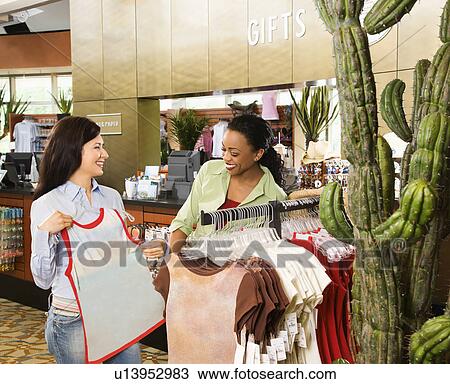 Stock Image - Two female friends shopping at a gift store together.. Fotosearch