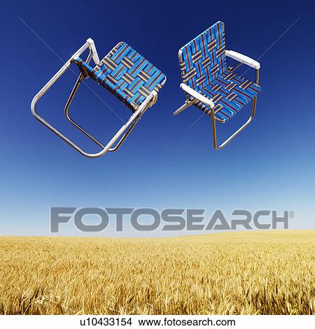 Two lawn chairs in mid-air above a field of wheat with blue sky. View Large Photo Image Picture - Two lawn chairs in mid-air above a field of wheat with blue sky.. Fotosearch