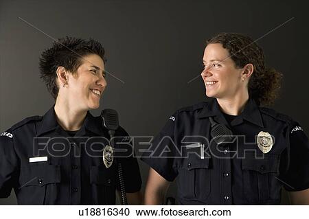 Two mid adult Caucasian policewomen standing looking at each other smiling. View Large Photo Image Stock Image - Two mid adult Caucasian policewomen standing looking at each other smiling.. Fotosearch