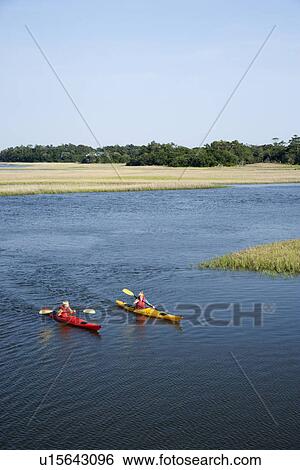 Stock Photograph - Two teenage boys kayaking through marshland on Bald Head Island, North Carolina.. Fotosearch