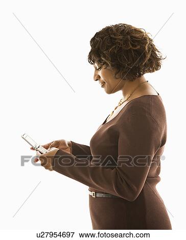 Stock Photo - Woman pushing buttons on cellphone standing against white background.. Fotosearch