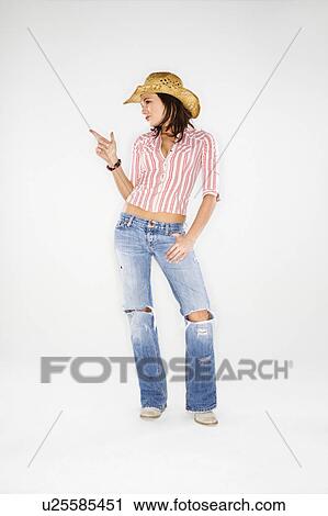 Stock Image - Young adult Caucasian woman wearing cowboy hat pointing finger like a gun.. Fotosearch