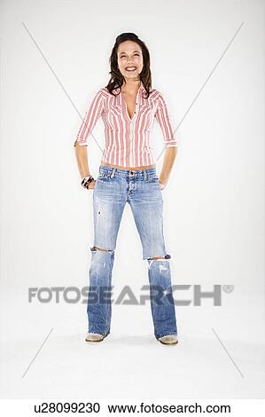Stock Image - Young Caucasian woman standing with hand on hips laughing.. Fotosearch