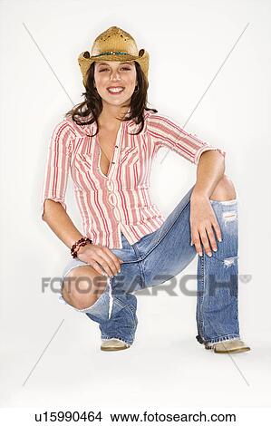 Young Caucasian woman wearing cowboy hat crouching and looking at viewer. View Large Photo Image Picture - Young Caucasian woman wearing cowboy hat crouching and looking at viewer.. Fotosearch