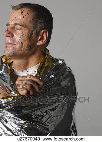 Mud covered man with thermal blanket View Large Photo Image Stock Photo - Mud covered man with thermal blanket. Fotosearch