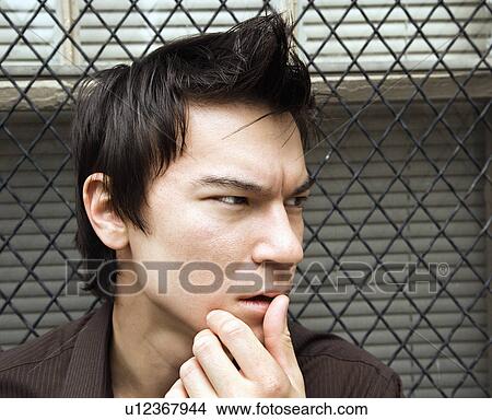 Picture - Asian man next to window looking off to side.. Fotosearch