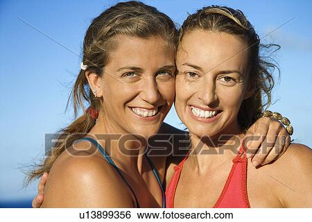 Stock Photograph - Caucasian mid-adult women holding each other smiling.. Fotosearch