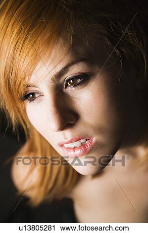 Stock Image - Close-up portrait of serious-looking young female looking off to the side.. Fotosearch