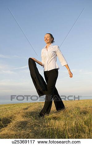 Stock Photo - Business woman walking across a field. Fotosearch
