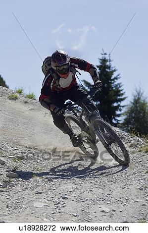 Stock Image - Downhill mountain biker riding fast. Fotosearch