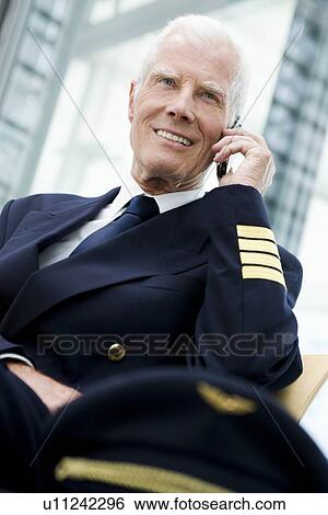 Stock Photograph - Flight captain using cell phone. Fotosearch
