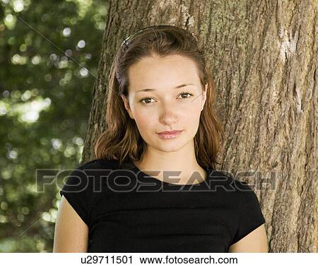 Stock Image - Girl leaning against a tree. Fotosearch