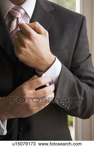 Stock Image - Male puts on cufflinks. Fotosearch
