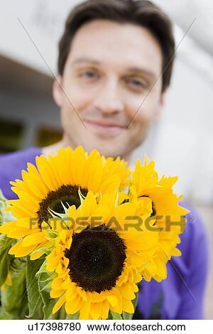 Stock Image - Man giving flowers to the viewer. Fotosearch